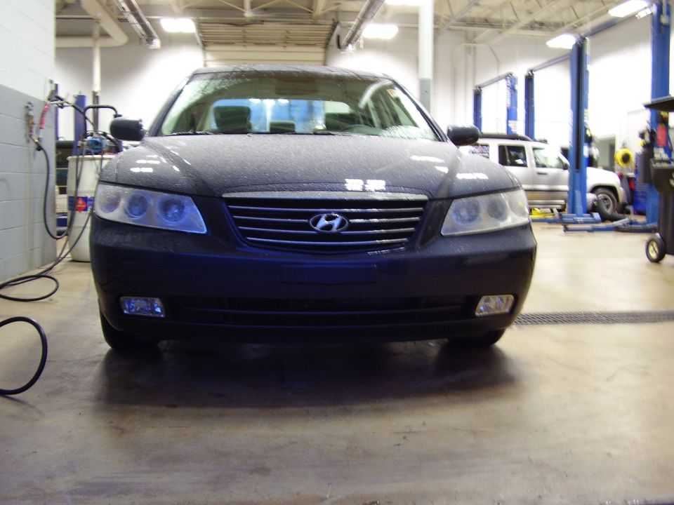 Hyundai Grandeur front view in a garage with a white SUV in the background