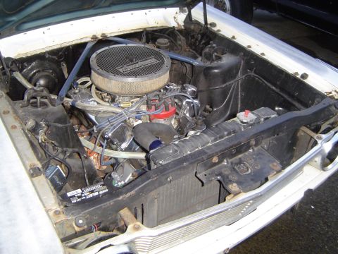 1964 Ford Fairlane - The engine bay of a 1964 Ford Fairlane shows its V8 engine, air filter, and radiator.