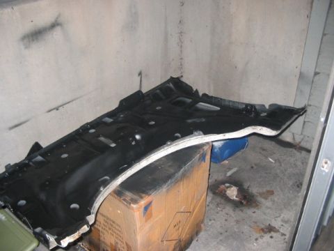 1991 Ford Bronco - A black car undercarriage part is seen resting on a cardboard box in a concrete room.