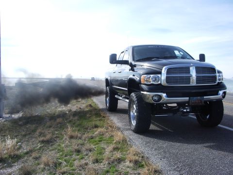 2005 Dodge 2500 - 2005 Dodge 2500 pickup truck driving on a road and emitting black smoke from the exhaust.