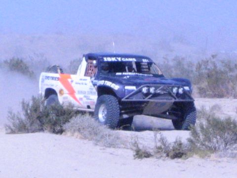 Blue race truck with lightning graphic and Isky Cams decals in desert
