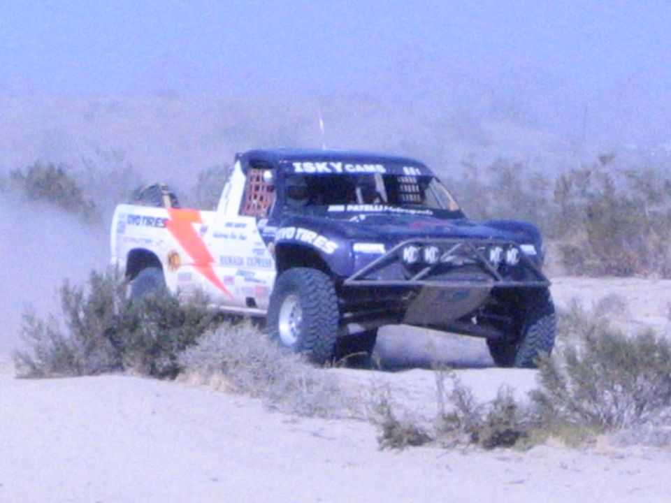 Blue race truck with lightning graphic and Isky Cams decals in desert