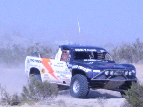 Blue and white off-road race truck with Toyo Tires and Isky Cams livery in desert