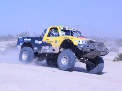 Yellow and blue race truck with BFGoodrich graphics jumping in the desert