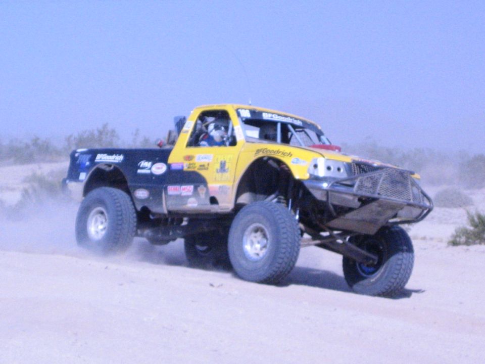 Yellow and blue race truck with BFGoodrich graphics jumping in the desert