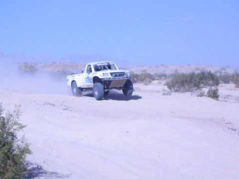 White off-road race truck racing along a sandy desert track