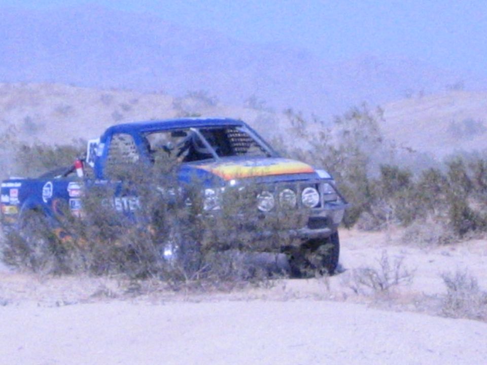 Blue race truck with sunburst hood and roof lights in scrubby desert