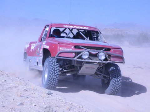 Red Ford race truck with Reagan Racing graphics on a sandy track