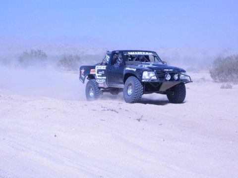 Black off-road race truck racing along a sandy desert track