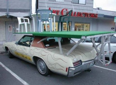 1966 Land Rover Discovery - A car is modified to carry a table and chairs on its roof, with another vehicle visible behind it.