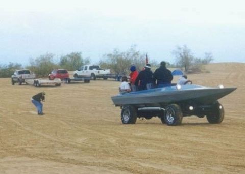 1966 Land Rover Discovery - Multiple vehicles are present in a desert landscape, including an amphibious vehicle with passengers.