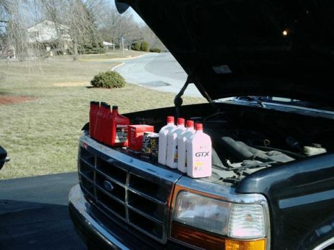 1992 Ford Bronco - Bottles of oil and other automotive fluids are lined up on the hood of a Ford truck with the engine exposed.
