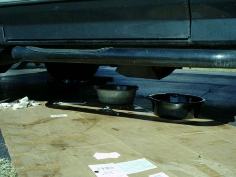 1992 Ford Bronco - Oil change in progress under a vehicle, with collection pans and tools laid out.