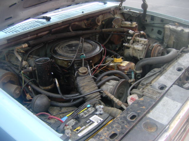 Engine bay of older vehicle with air cleaner, battery and accessory belts