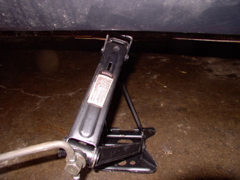 1990 Lincoln Town Car - A car jack is shown in use, positioned beneath the undercarriage of a vehicle.