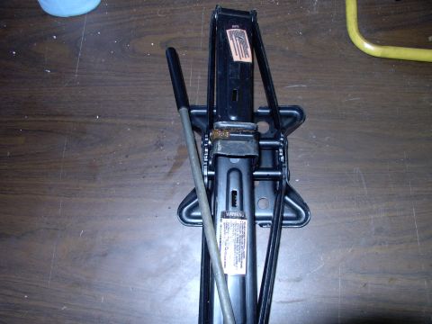 1990 Lincoln Town Car - A black scissor jack is shown, with a warning label visible on its central column.