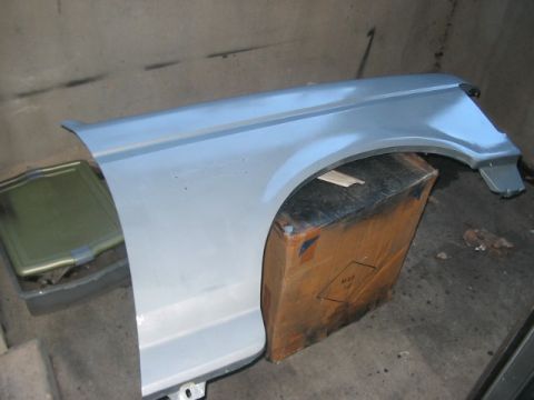 1991 Ford Bronco - A light blue vehicle fender is shown, resting on a cardboard box in what appears to be a garage or workshop.