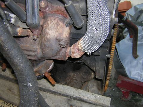 1979 Ford Bronco - Close-up view of an engine's exhaust manifold and a damaged flex pipe.