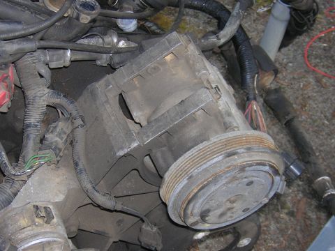 1979 Ford Bronco - This is a close-up view of a vehicle's air conditioning compressor, showing its pulley and surrounding engine components.