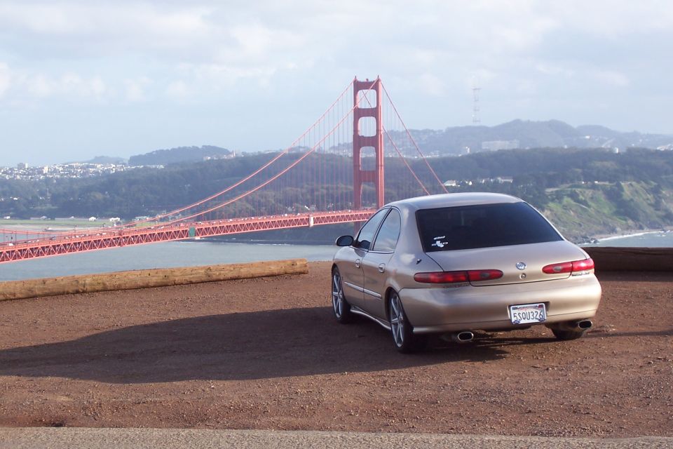 Gold Mercury Sable sedan parked, Golden Gate Bridge visible behind it. License plate 550U326