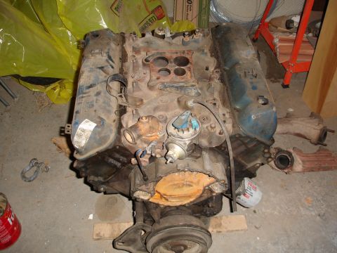 1979 Ford F-150 - A V8 engine with blue valve covers and a carburetor is shown in a workshop setting.