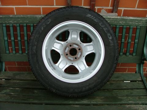 2001 Ford Fiesta - A single wheel and tire assembly is displayed on a weathered green bench.