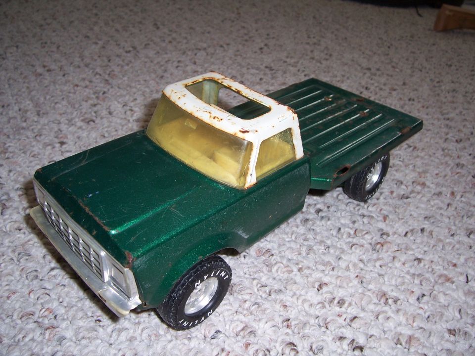 Green toy truck with a white roof and yellow windows, viewed from the front-right