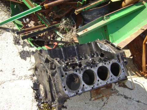 1992 Ford Bronco - A black engine block sits amidst scrap metal and debris, its cylinders exposed.