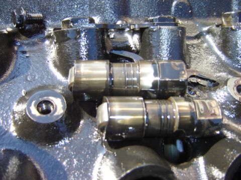 1992 Ford Bronco - Close-up view of engine valve lifters within a black engine block.
