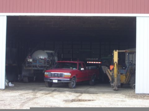 1992 Ford Bronco - A red 1992 Ford Bronco pickup truck is parked inside a barn with other farm equipment.