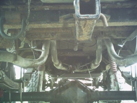 1986 Ford Bronco - A view of the undercarriage reveals a dual exhaust system and a trailer hitch, with visible rust.