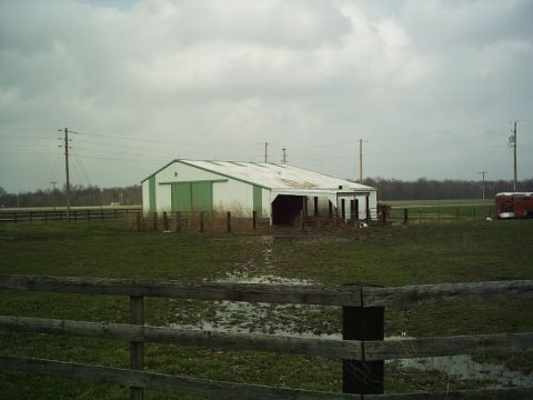 1986 Ford Bronco - A rural scene shows a barn and a trailer in a field with a wooden fence in the foreground.