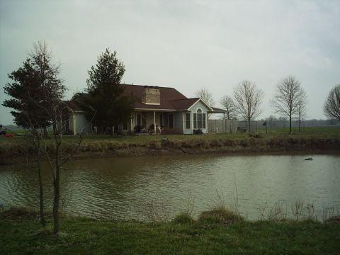 1986 Ford Bronco - A house sits beside a pond on an overcast day, with bare trees in the background.