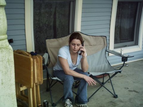 1986 Ford Bronco - A woman sits on a folding chair on a porch, talking on a cell phone.