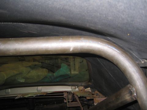 1969 Ford Mustang - Raw steel roll bar hoop fitted inside a vehicle cabin during fabrication, showing the hoop arching over the rear window opening with the st…