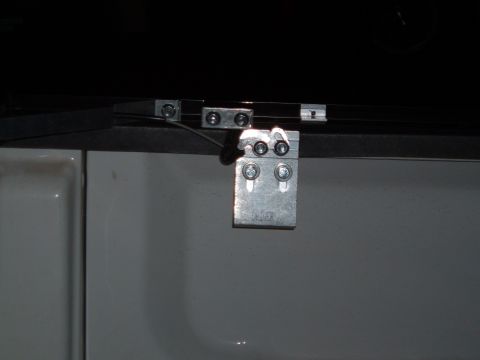 2003 Ford F-150 - Close-up of a tonneau cover hinge attached to the side of a white truck bed.