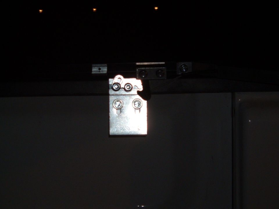 Close-up of a metal hinge on a dark surface, possibly a truck bed