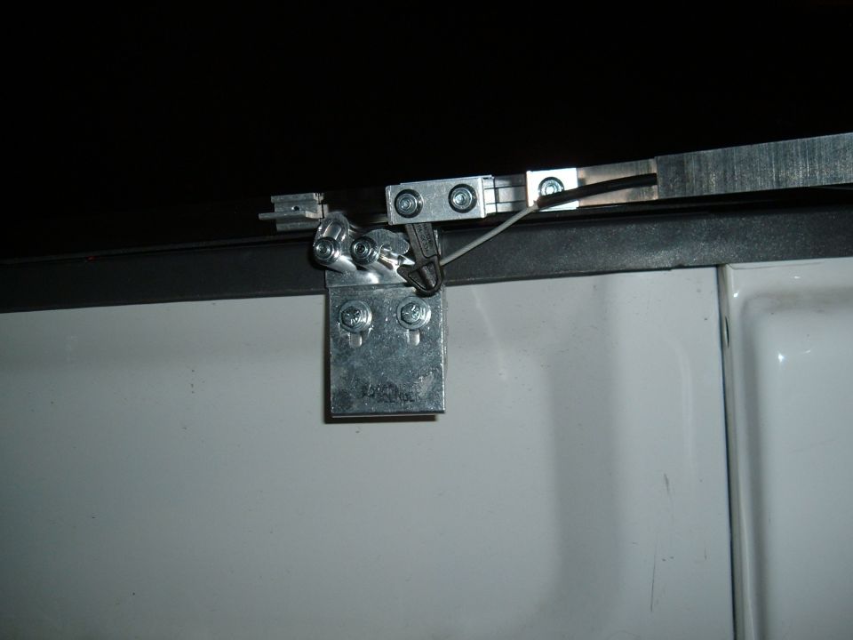 Close-up of a tonneau cover latch mechanism with metal brackets and a cable