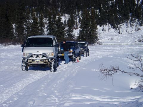 2000 Ford E350 - Three vehicles, including a 2000 Ford E350 van, are parked in a snowy landscape with trees in the background.