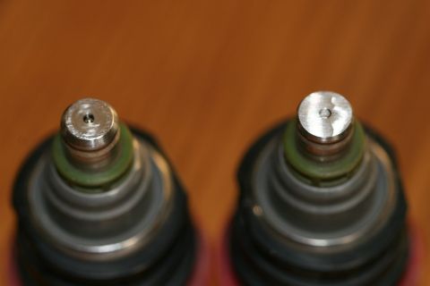 1996 Ford Probe - Close-up view of two fuel injectors, showing their metallic tops and green seals against a wooden background.