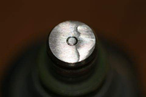 1996 Ford Probe - A detailed view of a metal fuel injector, showing its top surface and a central opening.
