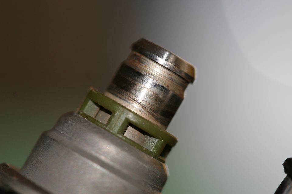 Close-up of a fuel injector with a green plastic collar