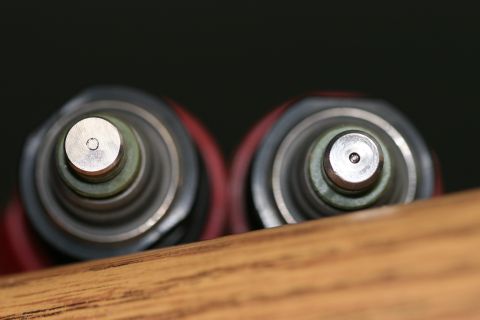 1996 Ford Probe - Two fuel injectors are shown from the top, resting on a wooden surface against a dark background.
