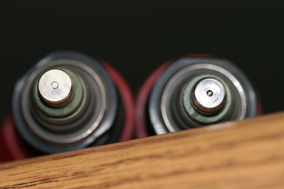 Close-up of two fuel injectors, showing their tops with small holes