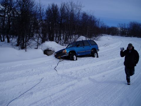 2000 Ford E350 - A blue SUV is stuck in a snowy ditch while a person films the scene.