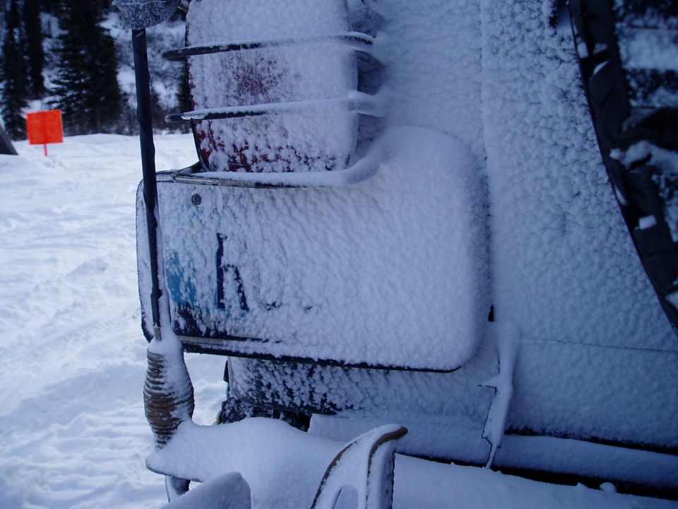 Vehicle rear corner covered in snow, showing a taillight and part of a license plate