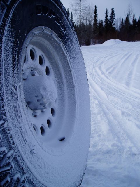 2000 Ford E350 - A vehicle's tire is covered in snow, parked in a snowy landscape with tracks leading away.