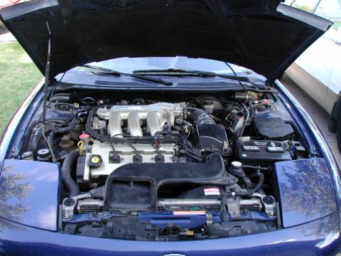 1994 Ford Probe - The engine bay of a blue car is shown with the hood open, revealing the engine components and a Supermotors.net watermark.