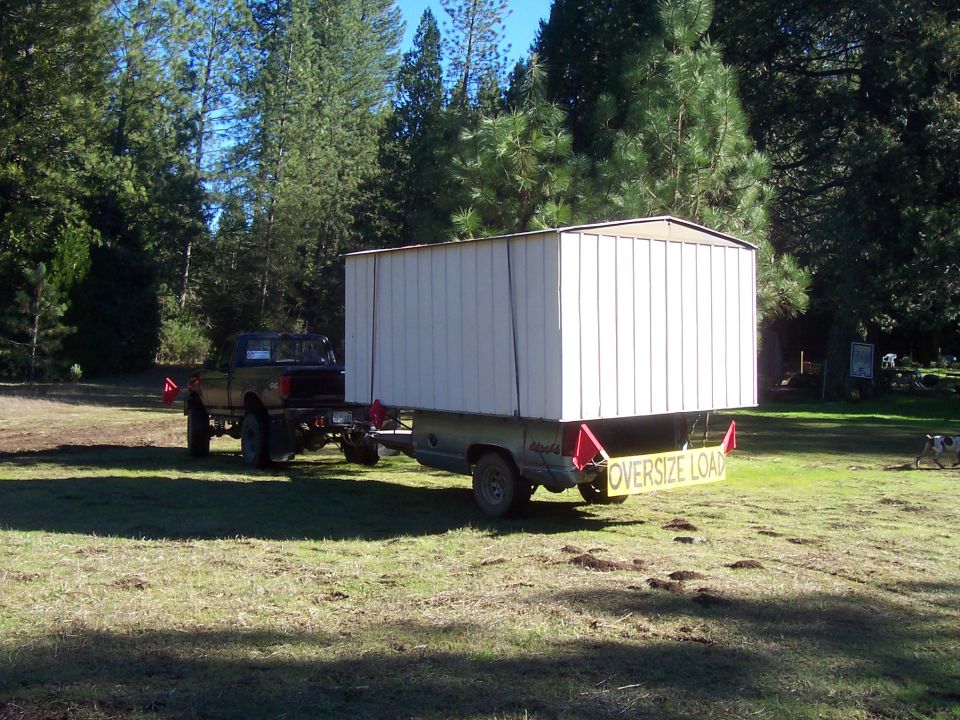Truck towing a large white enclosed trailer with an 'OVERSIZE LOAD' sign on the back