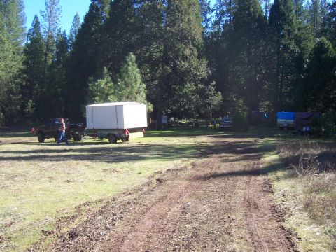 1994 Ford F-150 - A truck tows a trailer with a large white box through a wooded area.